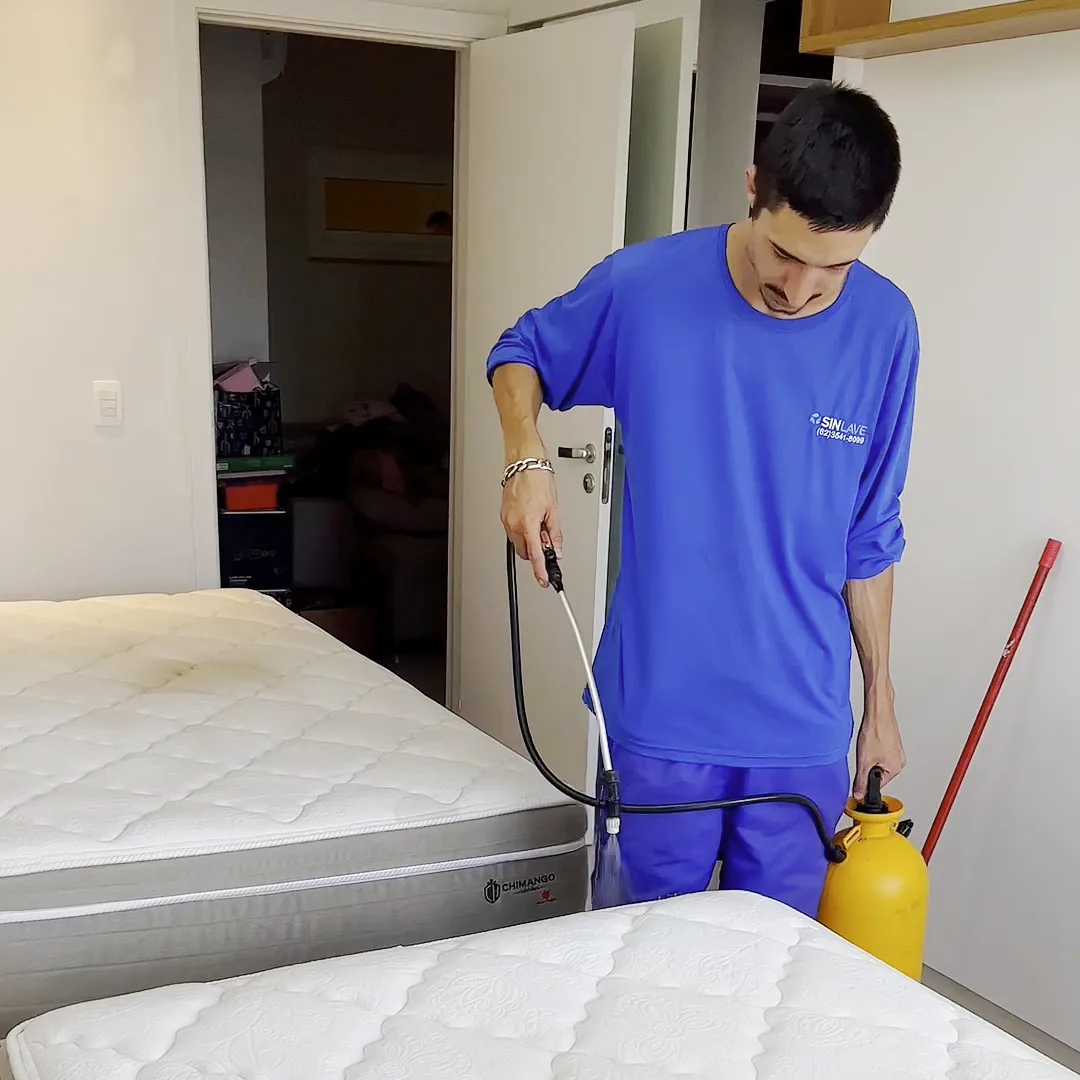 Técnico da Sinlave borrifando o produto num colchão branco com o pulverizador