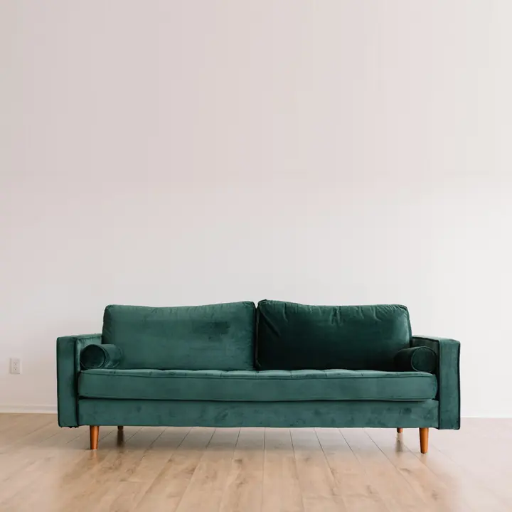 Sofá verde de tecido de pelo curto em sala vazia (imagem ilustrativa)