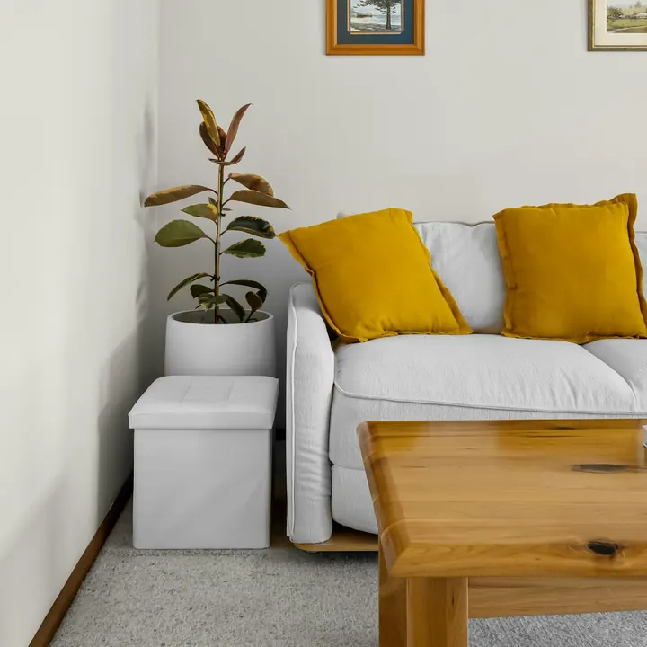 Sofá branco com almofadas amarelas e mesa de centro de madeira (imagem ilustrativa)