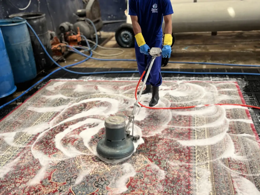 Tapete persa vermelho sendo lavado com equipamento industrial na lavanderia da Sinlave em Goiânia