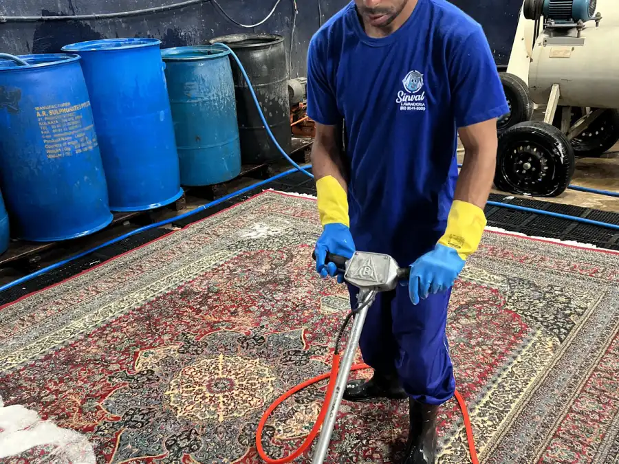 Integrante uniformizado da Sinlave lavando um tapete persa na lavanderia